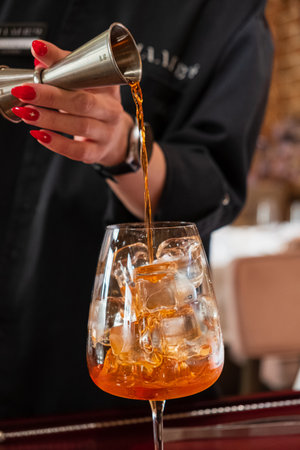 A bartender pours a colorful drink over ice into a stylish glass at a modern bar.の写真素材