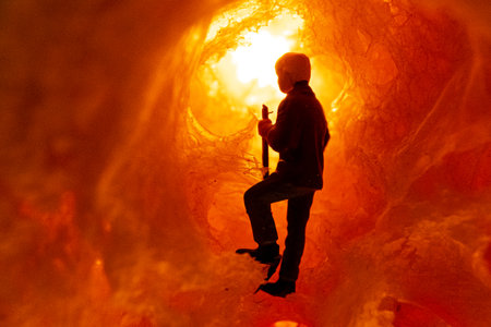 A solitary figure stands inside a glowing cavern, exploring the warmth and mystery around.の写真素材