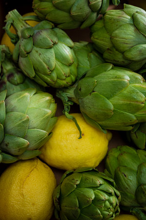 Fresh green artichokes surround vibrant lemons, showcasing natural produce in a cozy atmosphere.の写真素材