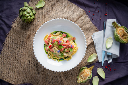 A vibrant pasta primavera with fresh veggies and edible flowers on a textured backdrop.の写真素材