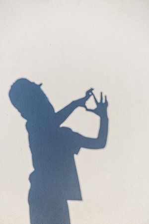 A child's joyful shadow forms playful shapes against a bright, sunlit wall.の写真素材