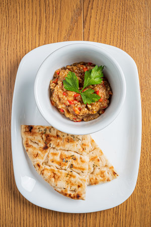Delicious eggplant dip garnished with herbs served alongside warm, grilled flatbread.