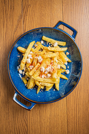 Delicious crispy fries sprinkled with spices and cheese sit on a vibrant blue dish.