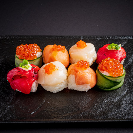 Assorted sushi rolls on a sleek black platter invite a vibrant taste experience.の写真素材