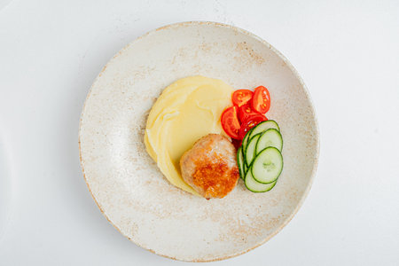 Delicious meatball served with smooth mashed potatoes and crisp cucumber and tomato slices.