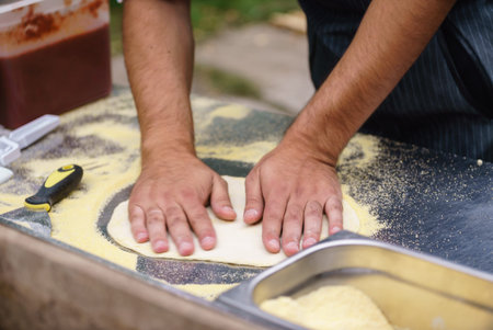 Artisan kneads dough with focus, immersed in the lively market atmosphere.