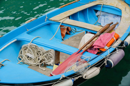 Colorful boat rests quietly on clear water, inviting journeys with its paddles and fishing gear.