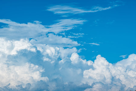 Fluffy white clouds float serenely in the clear blue sky, inviting daydreams and inspiration.