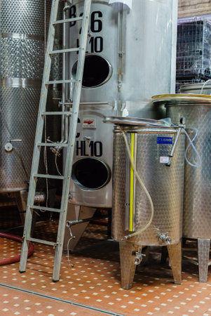 A charming vineyard cellar showcases metallic tanks and a ladder, hinting at winemaking magic.