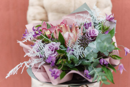 A person holds a stunning bouquet filled with colorful flowers and lush greens, bringing joy.の写真素材