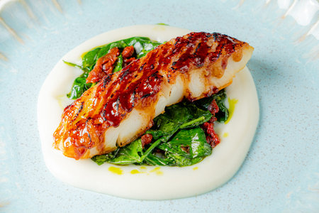 Savor the rich flavors of grilled fish served elegantly on vibrant spinach and creamy puree.