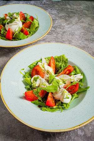 Colorful salad featuring ripe tomatoes, crisp greens, and a drizzle of creamy dressing on top.