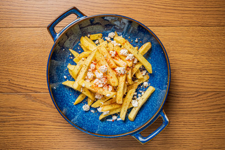 Freshly cooked fries served in a colorful bowl, sprinkled with cheese and spices for flavor.