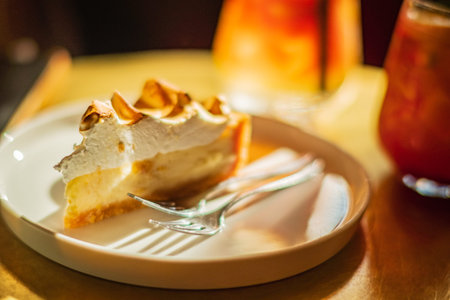 A slice of lemon meringue pie sits beside a cold drink, exuding a cozy vibe.