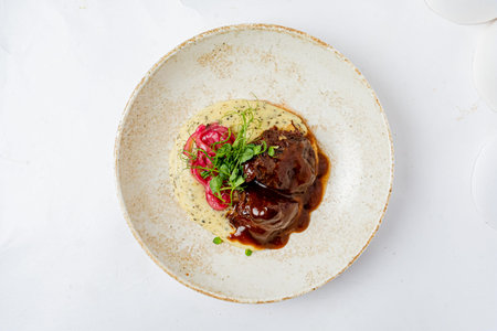 Tender beef in rich sauce with creamy mashed potatoes and vibrant greens makes a delightful meal.