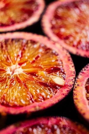 Juicy blood orange slices lay arranged, showcasing rich hues and glistening juice, inviting taste.