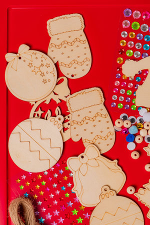 Crafting colorful wooden holiday ornaments on a vibrant red surface, full of creativity and joy.