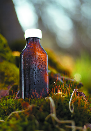 Herbal essence. Alternative healthy medicine.  Fresh herbs in a medical brown bottleの写真素材