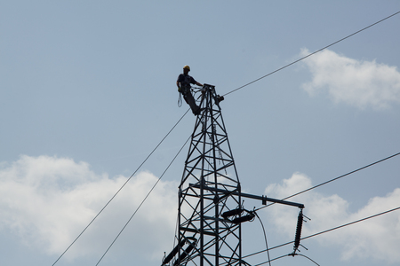 Electrician repair of electric power system. Electrician climbing poles, repairing power lines.の写真素材