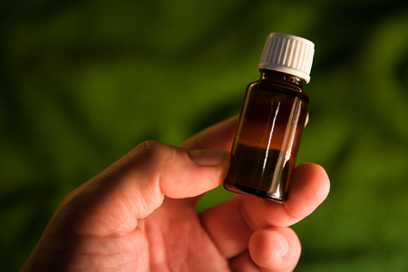 Brown glass medicine bottle with hand. Hand with small glass bottle. Natural remedies -  Space for text.の写真素材