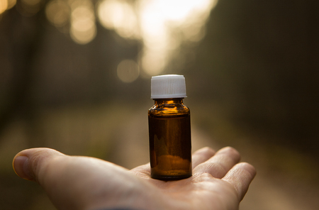 Hand with small glass bottle. Amber glass medicine bottle with hand - space for text.の写真素材