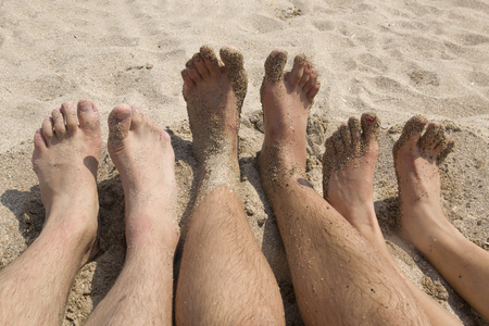 The feet relax on the beach. Three people lying on the beach.の写真素材