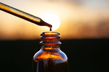 Pipette dropper of aromatherapy essence over brown glass bottle. Dropper and Brown Glass Bottle - sunsetの写真素材