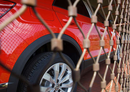 POZNAN, POLAND - May 17, 2019: Transportation of cars by train. New red car behind bars, metal mesh.のeditorial素材