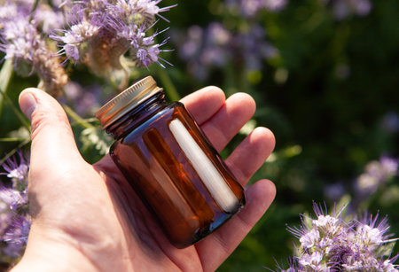 Concept - natural medicines, herbal pill. Tablets in a glass bottle in hand.