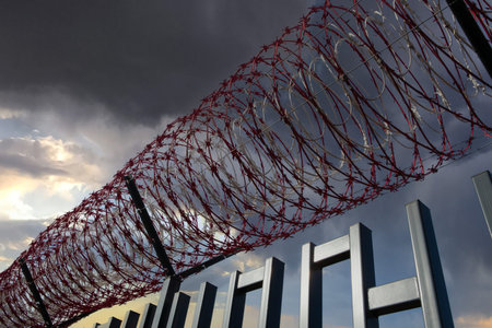 Coil of razor barbed wire as barricade against trespasser on a gloomy cloudy sky.