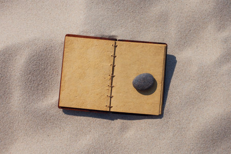 Open old book with seashells on the sand. Summer time.