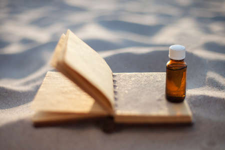 Open old book with seashells on the sand. Bottle on sand. Copy spaceの写真素材