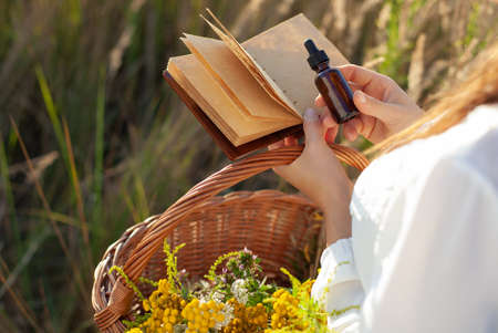 Herb extract in a dropper, copy-space for text. Woman holding a medical bottle and a blank notebook in her hand. Natural Remedy, conceptul - MOCK-UP.の写真素材