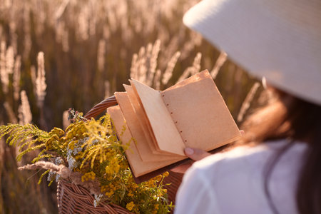 A girl in a stylish summer dress feels at ease in a field of tall grass in the sun. Copy-space.の写真素材