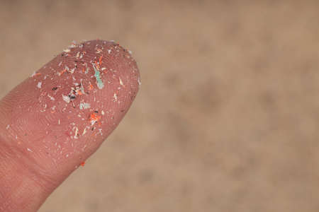 Close-up of microplastics lay on finger of human being. Concept of water pollution and global warming. Idea for climate change.の写真素材