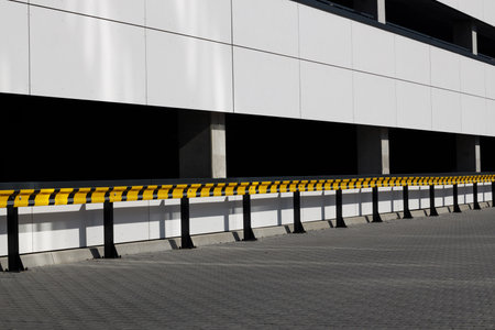 Yellow and black guardrails outside building, parking lot.の写真素材