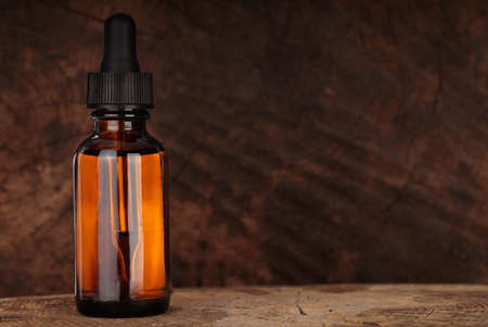 Cosmetic bottle with pipette on wooden table. Wooden beard oil in dropper. MOCKUPの写真素材