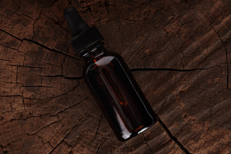 Amber glass complementing bottle on wooden background. Medical package, concept of herbal medicine.