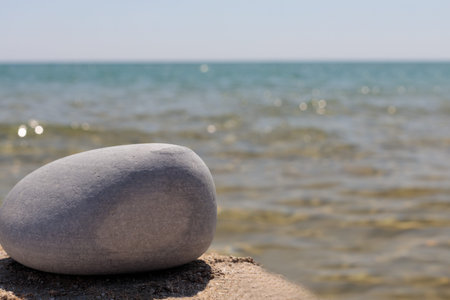 An empty product template on a stone rocky pedestal in front of an ocean background, creating a...