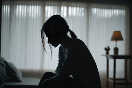 A person sitting in a dark room, surrounded by the shadows of their own despair and loneliness.の素材