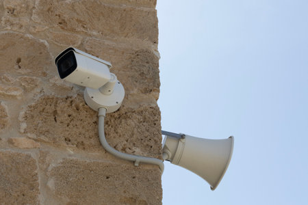 Surveillance Camera and Loudspeaker on Stone Wallの写真素材