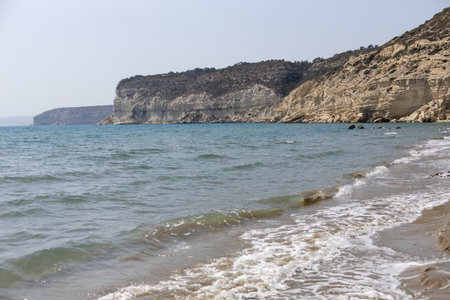 A sandy beach with gentle waves on the Cyprus coast, showcasing cliffs.の写真素材