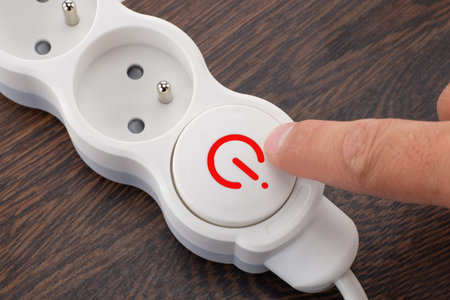 Person Pressing Power Button on Power Strip