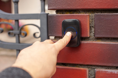 Hand Pressing Doorbell on Red Brick Wall