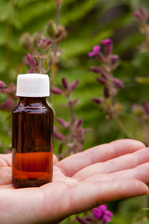 Small Amber Glass Bottle Held in Hand Outdoorsの写真素材
