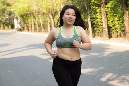 Fat woman running exercise smile face in park weight loss conceptの写真素材