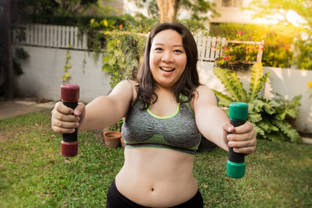 Fat woman happy fun face exercise weight loss concept at home with lift dumbbellの写真素材