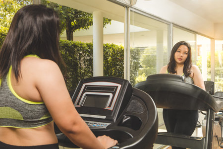 Fat Woman weight loss running on treadmill mirror reflect face smile happy to exercise in fitness gymの写真素材