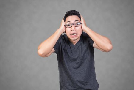 man scream shocked face hand on head grey backgroundの写真素材