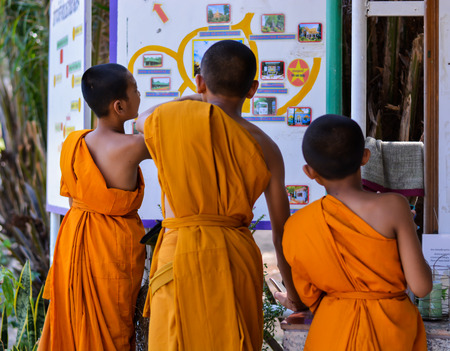 ROI Et THAILAND : Three unidentified young monks are looking at the map of Maha Chedi Chai Mongkol temple where is one of the largest chedis pagoda in Thailand. It is located on the grounds of the Wat Pha Namthip Thep Prasit Vararam a temple complex in Roのeditorial素材